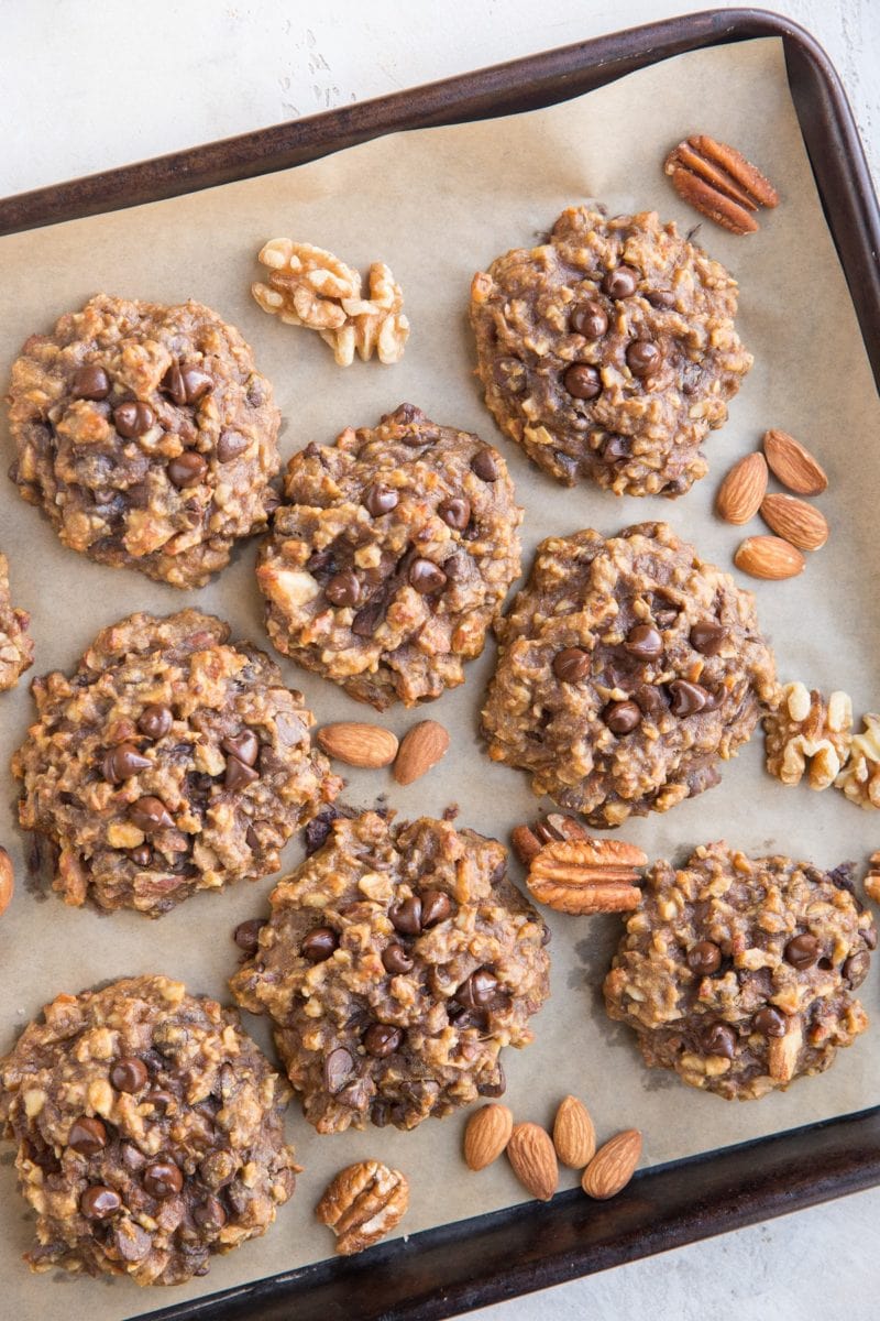 Parchment lined baking sheet with banana cookies and raw nuts between the cookies