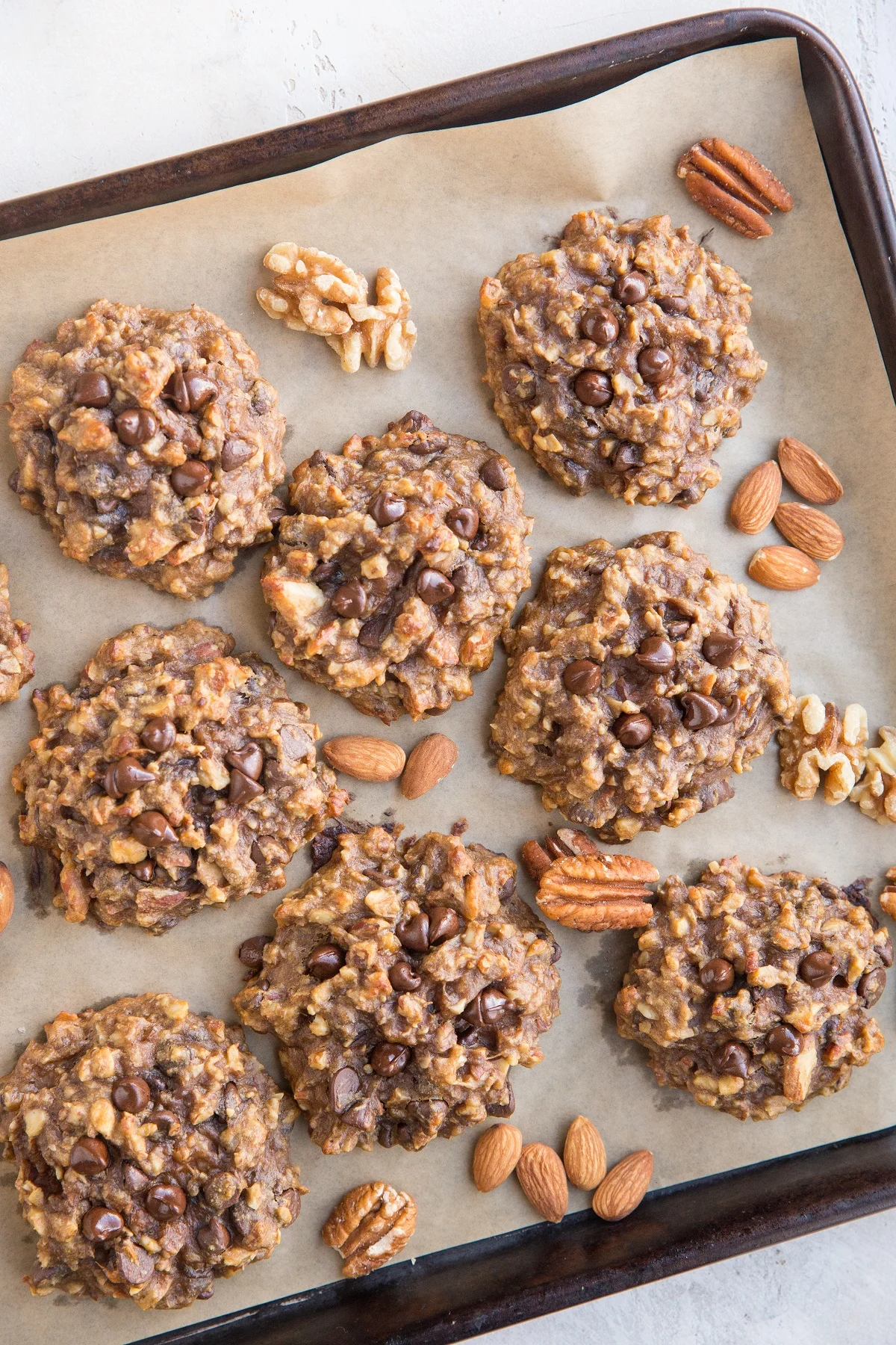Parchment lined baking sheet with banana cookies and raw nuts between the cookies