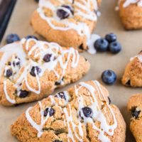 Baking sheet of blueberry almond flour scones with fresh blueberries and a glaze