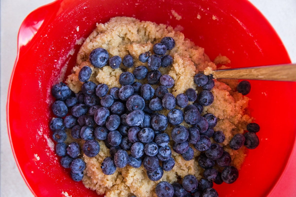 Mixing bowl with scone dough with fresh blueberries being mixed in
