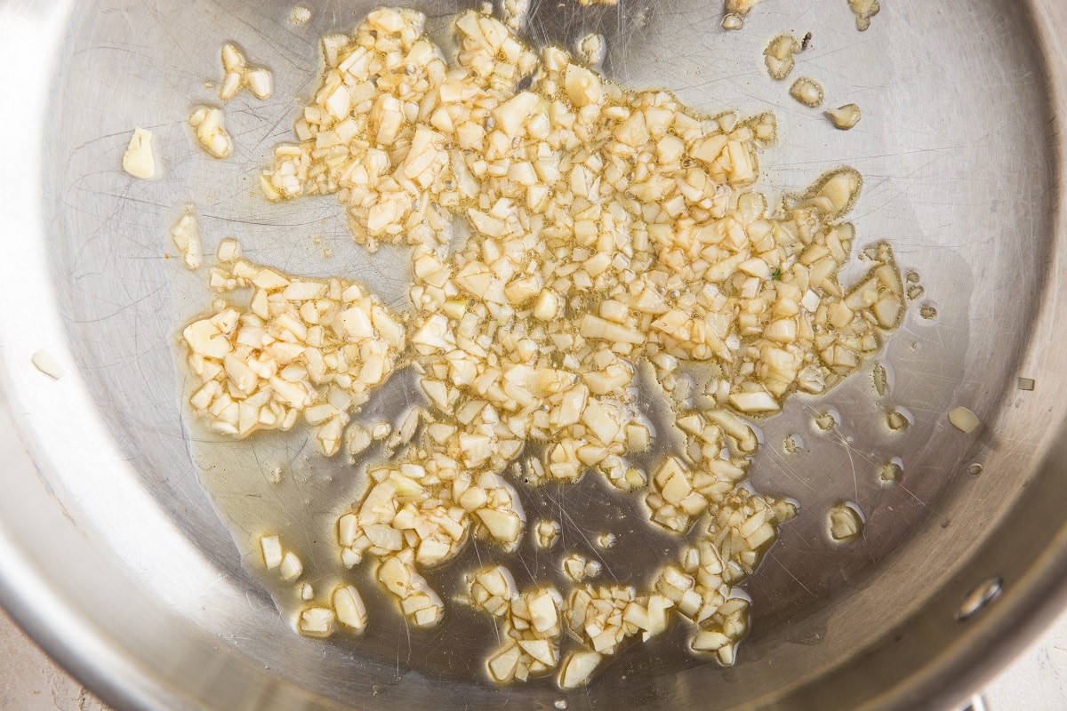 Garlic sautéing in a stainless steel skillet.