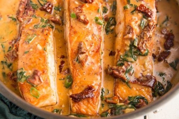 Horizontal photo of creamy tuscan salmon in a stainless steel skillet