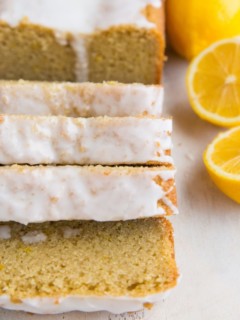 Keto Lemon Pound Cake in slices on a white surface with lemon halves next to it