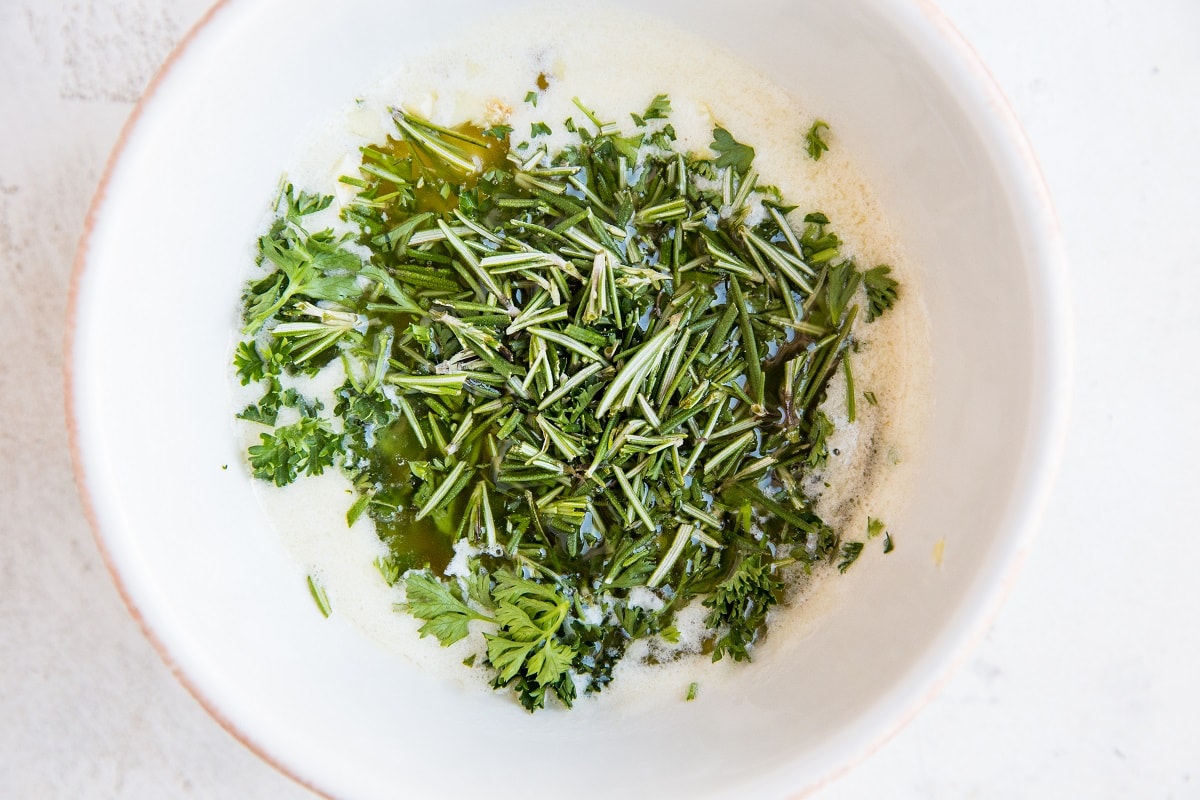 Ingredients for garlic herb butter in a white bowl