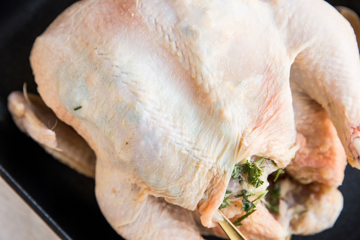 Inserting the garlic herb butter underneath the skin using a spoon