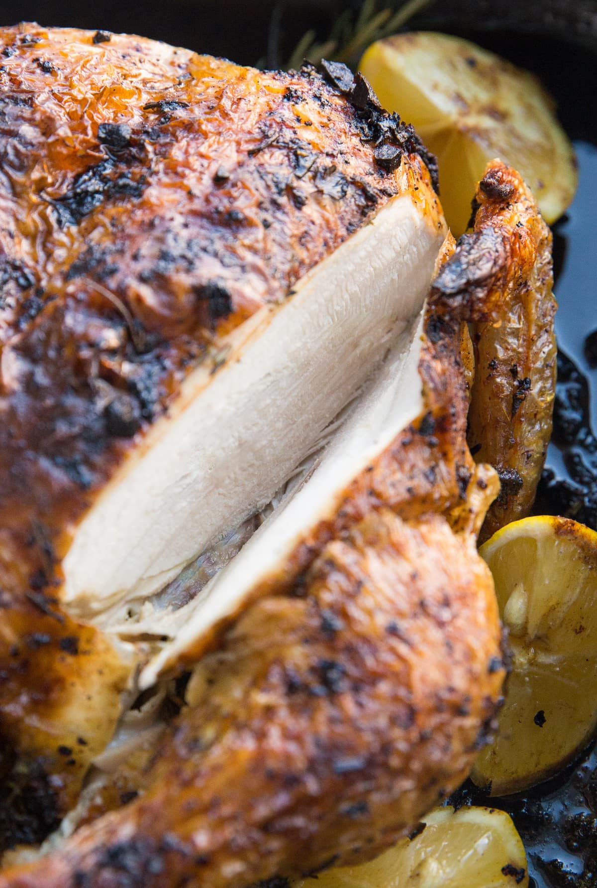 Roast chicken in a large roasting pan with a slice through the breast to expose the inside