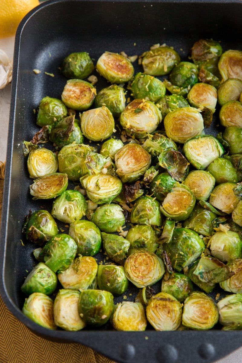 2 pounds of roasted brussel sprouts in a casserole dish with lemon zest on top
