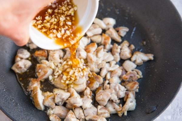 Pouring the honey garlic sauce into the skillet with the chicken