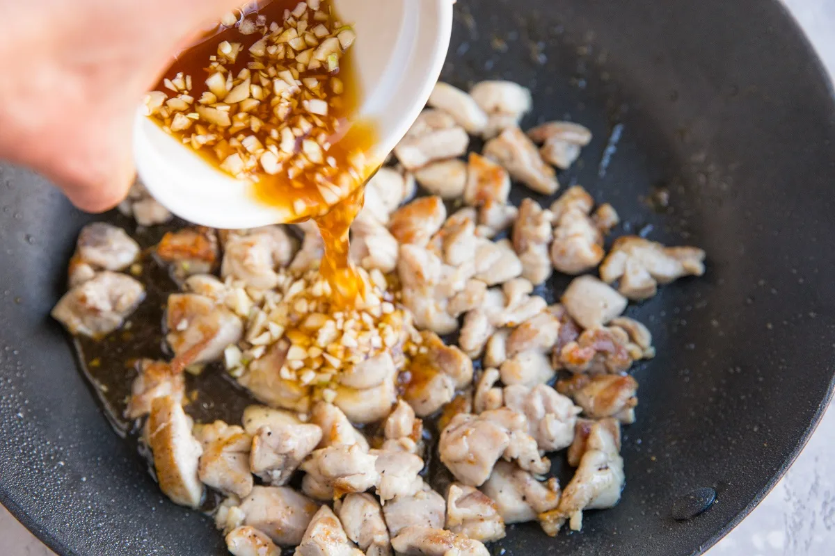 Pouring the honey garlic sauce into the skillet with the chicken