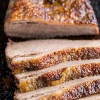 Close up image of sliced brisket on a baking sheet.