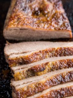 Close up image of sliced brisket on a baking sheet.