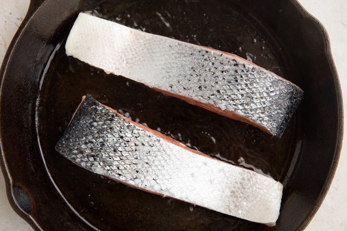 Salmon flesh-side down cooking in a cast iron skillet