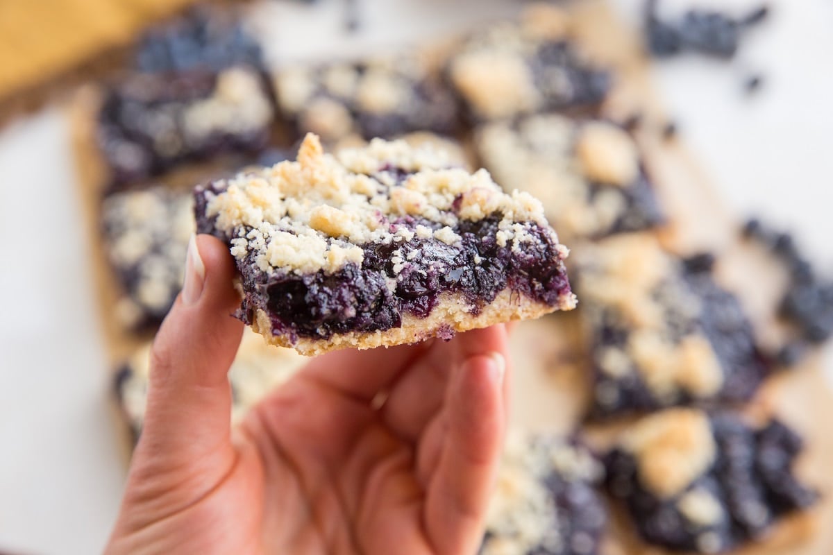 hand holding a blueberry crumb bar to get a side visual of the bars