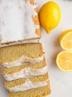 Top down photo of a loaf of lemon pound cake that has been cut into slices. Fresh lemons to the side