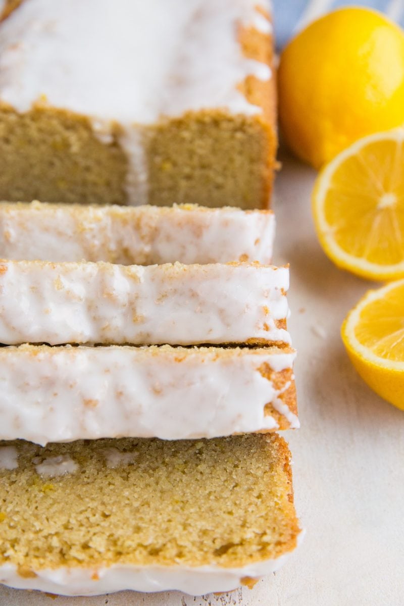 Keto Lemon Pound Cake in slices on a white surface with lemon halves next to it