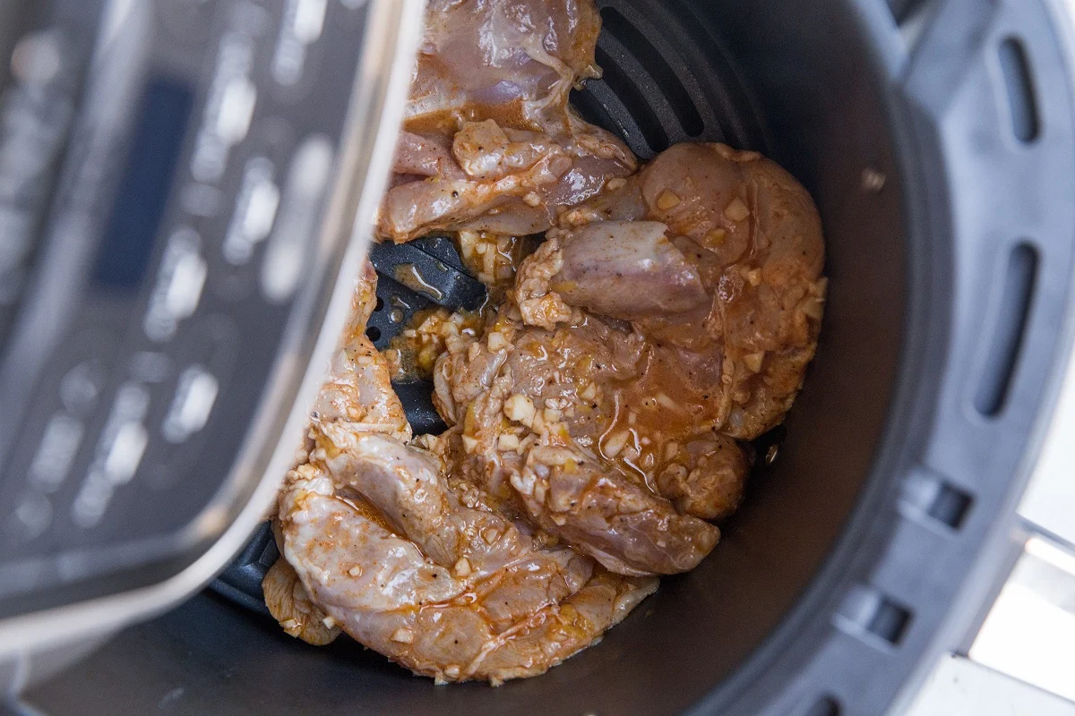 Raw chicken thighs in the air fryer in a single layer