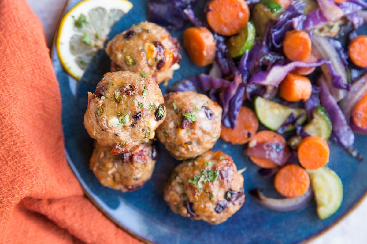 top down horizontal photo of blue plate of meatballs and veggies.