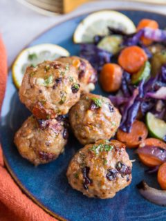 Mediterranean meatballs on a blue plate next to sautéed vegetables