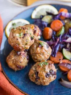 Mediterranean meatballs on a blue plate next to sautéed vegetables