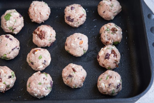 Raw meatballs in a casserole dish ready to go into the oven