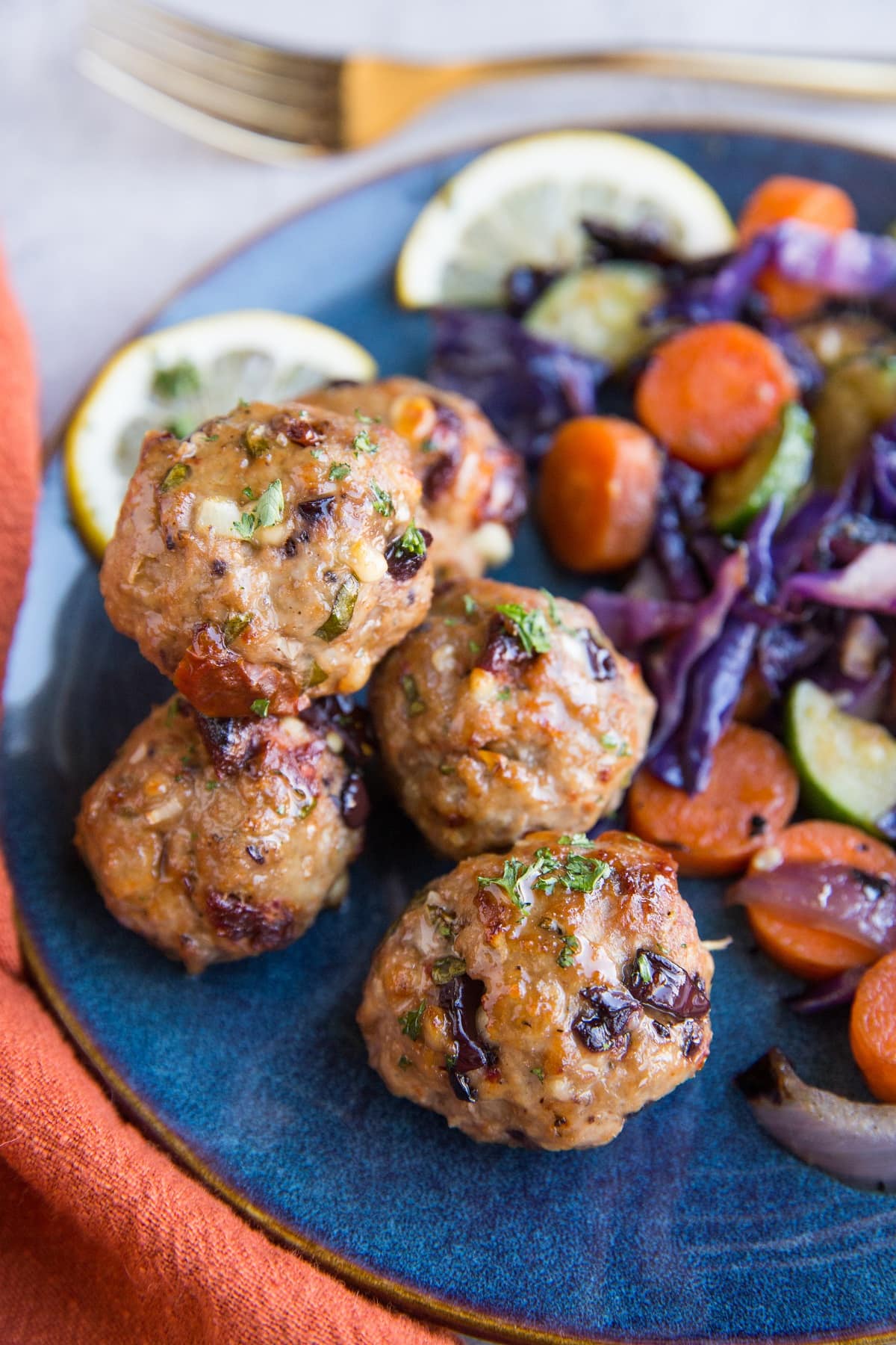 Mediterranean meatballs on a blue plate next to sautéed vegetables