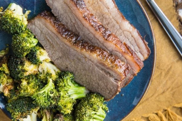 Slices of brisket on a plate with roasted broccoli