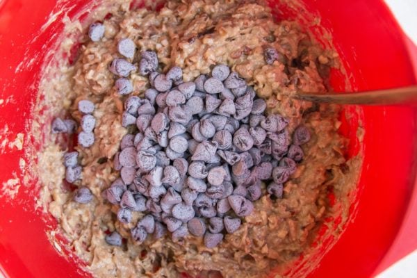 Cookie dough in a mixing bowl with chocolate chips on top ready to be stirred in