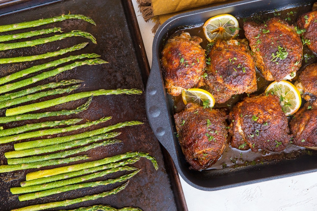 casserole dish of chicken and baking sheet of asparagus