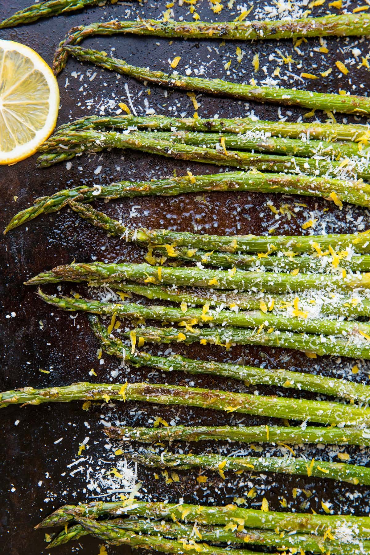 Roasted asparagus on a baking sheet with parmesan cheese and lemon zest