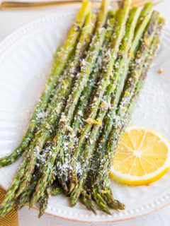 Plate of roasted asparagus sprinkled with lemon zest and parmesan