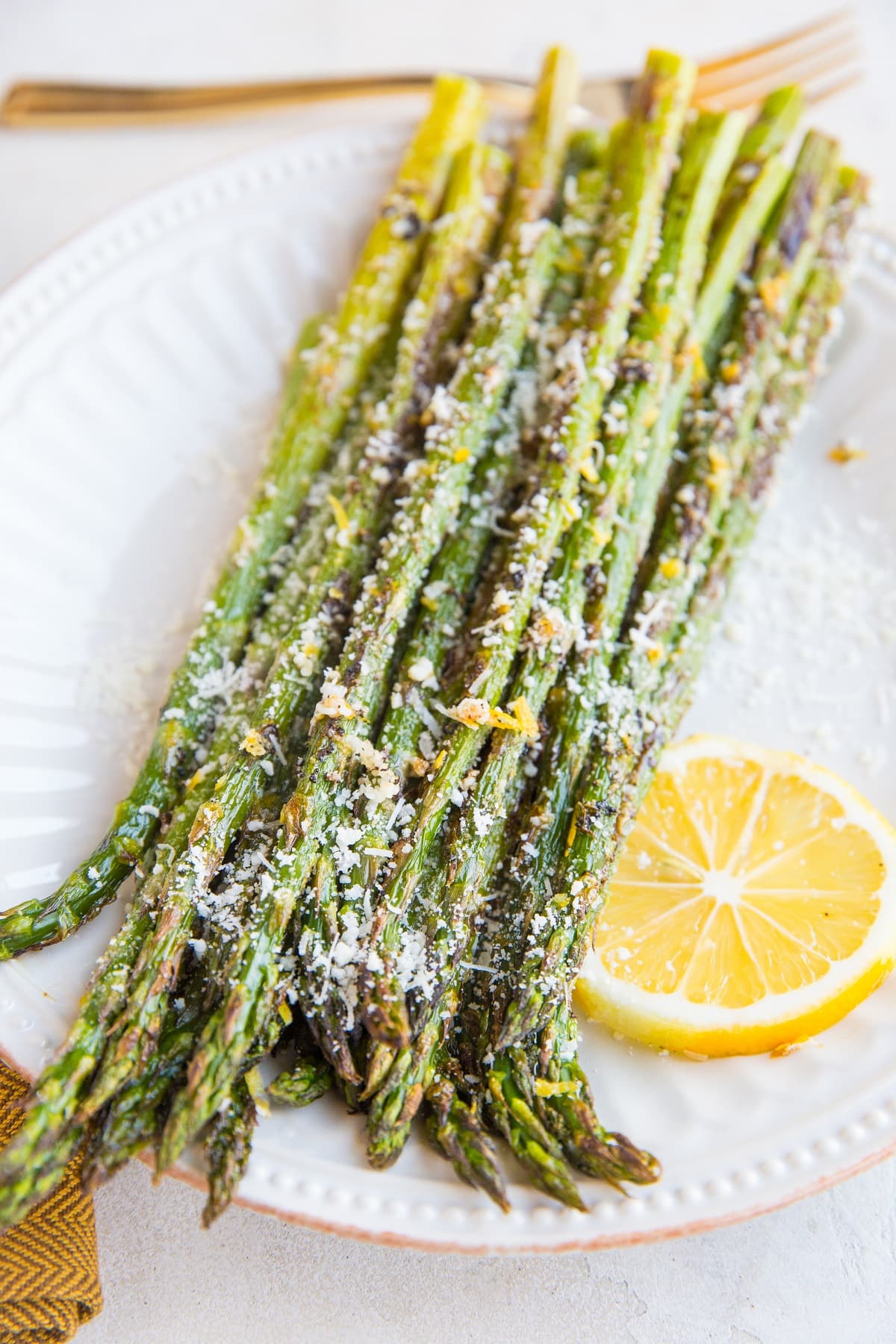 Plate of roasted asparagus sprinkled with lemon zest and parmesan