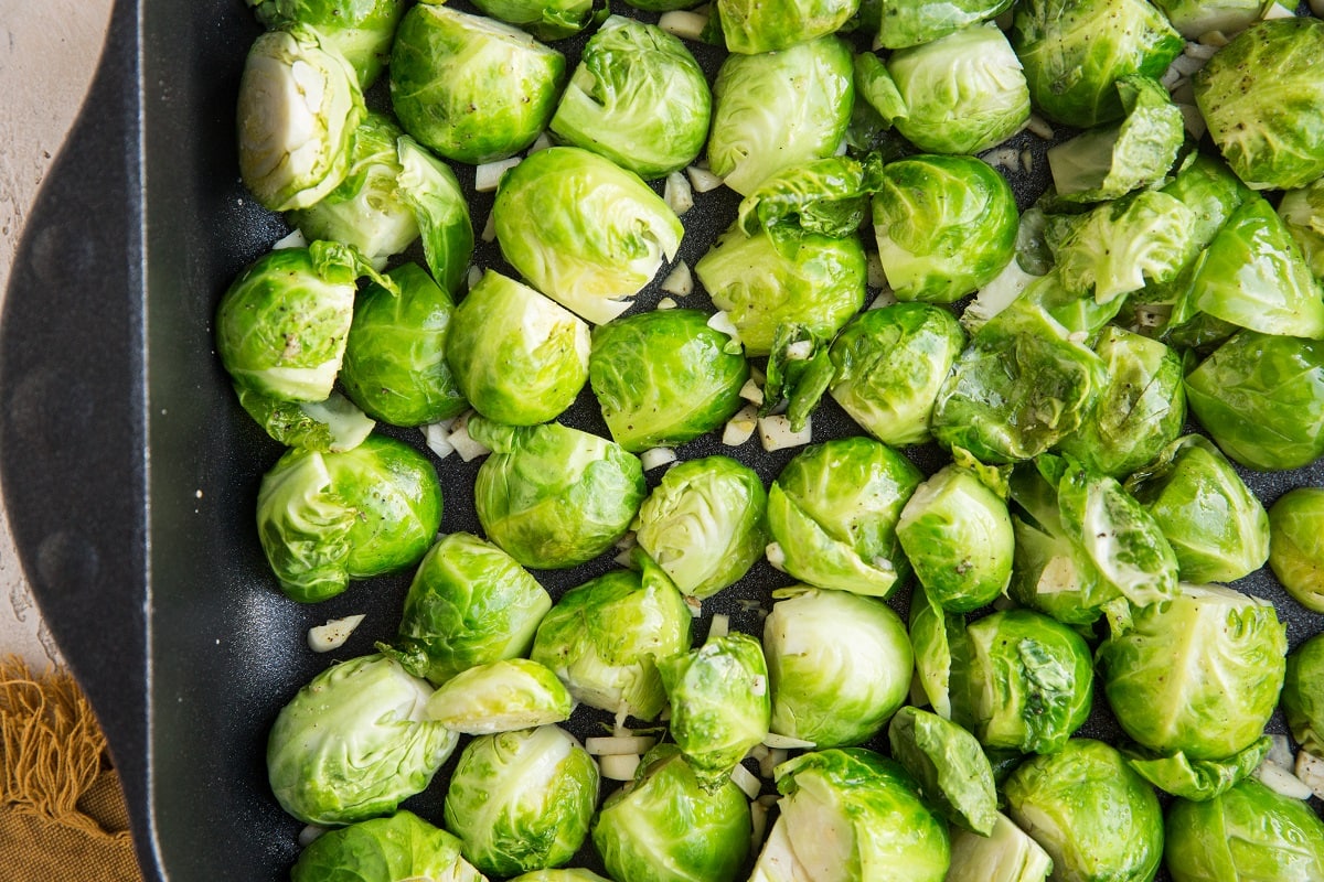 Casserole dish full of brussel sprouts with garlic mixed in