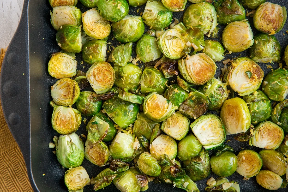Finished roasted brussels sprouts in a casserole dish with garlic and lemon zest