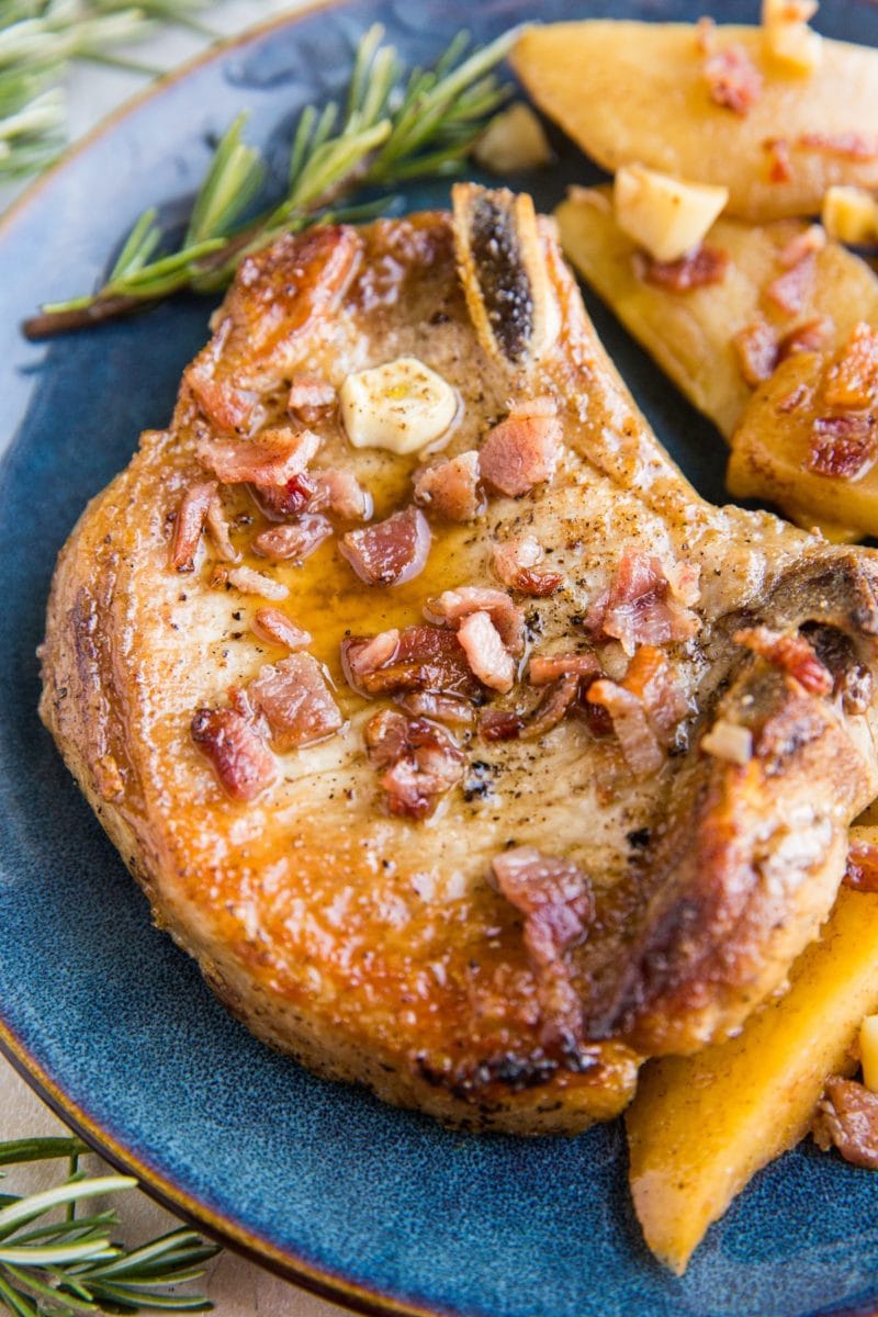 Close up image of roasted pork chop on a plate with bacon sprinkled on top