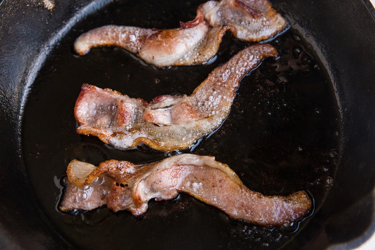Three strips of bacon in a cast iron skillet