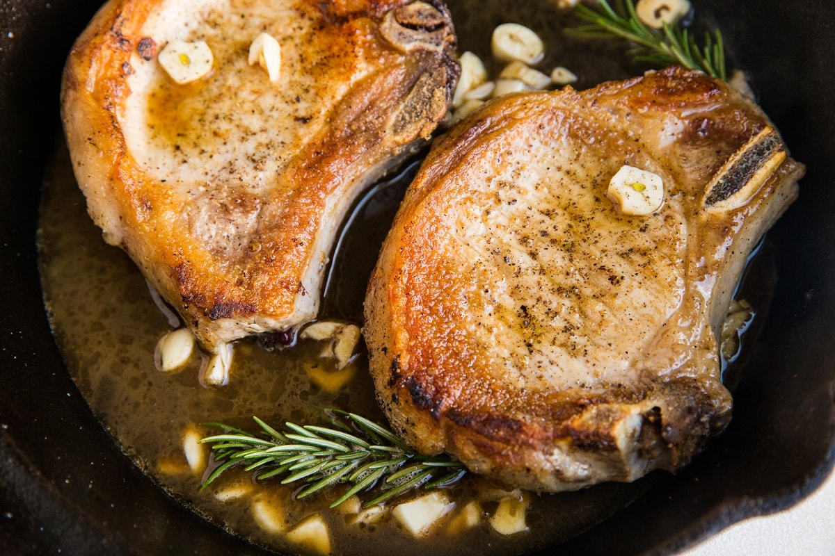Pork in a skillet with rosemary and garlic