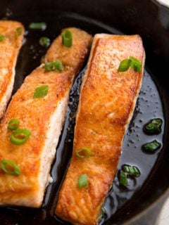 Pan-seared salmon in a cast iron skillet with bits of green onion on top