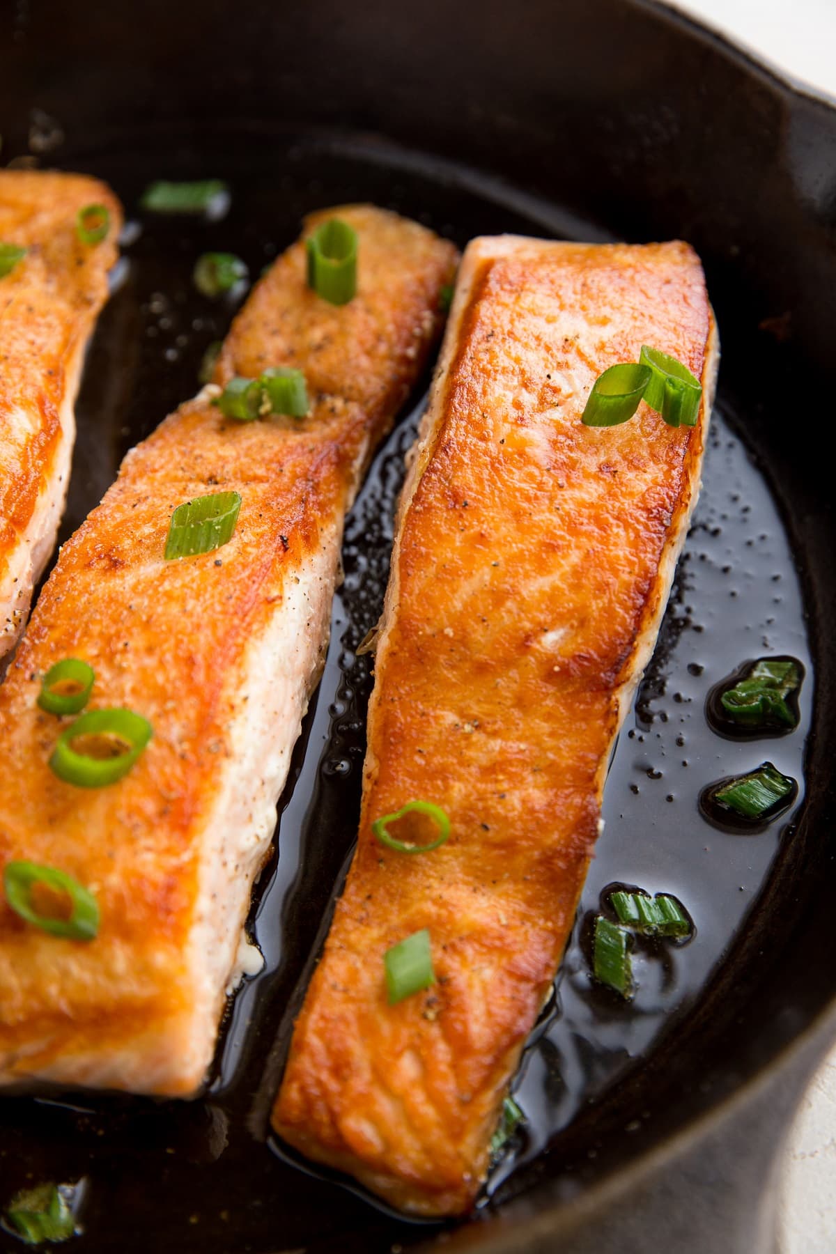 Pan-seared salmon in a cast iron skillet with bits of green onion on top