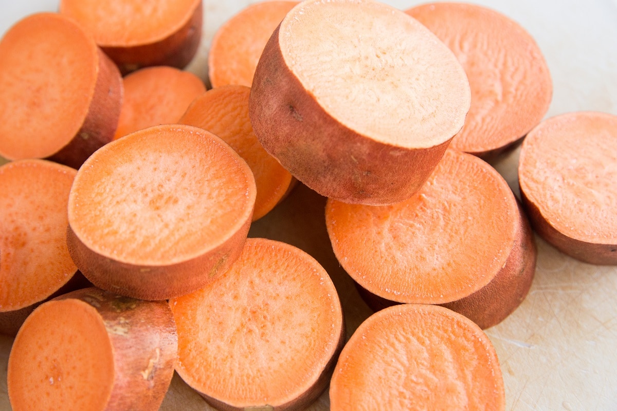 Sweet Potatoes that have been cut into 1-inch rounds on a cutting board