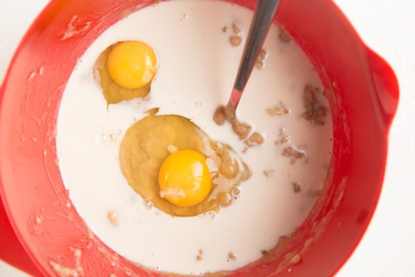 mixing bowl with mashed banana, almond butter, oat milk, and eggs