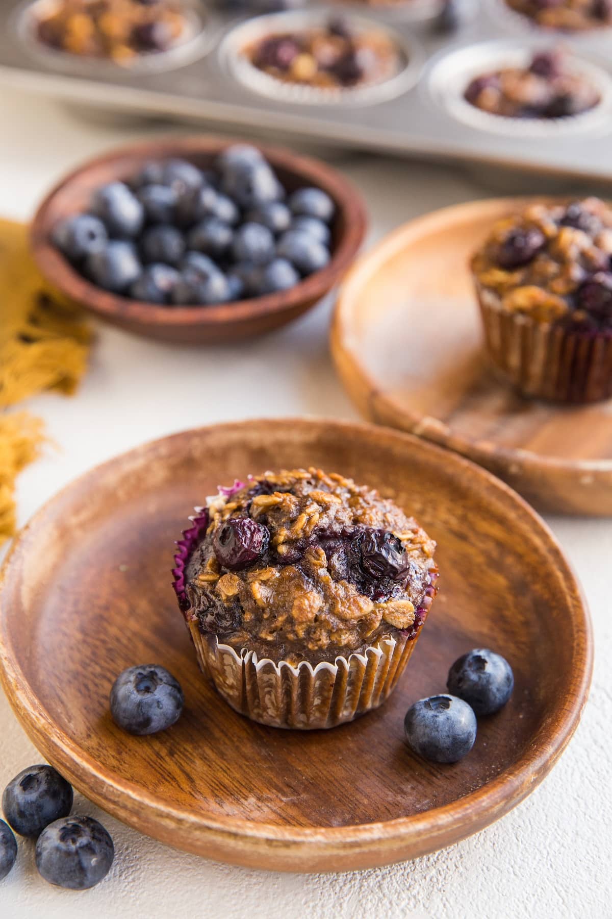 two oatmeal cups on wooden plates with blueberries to the side