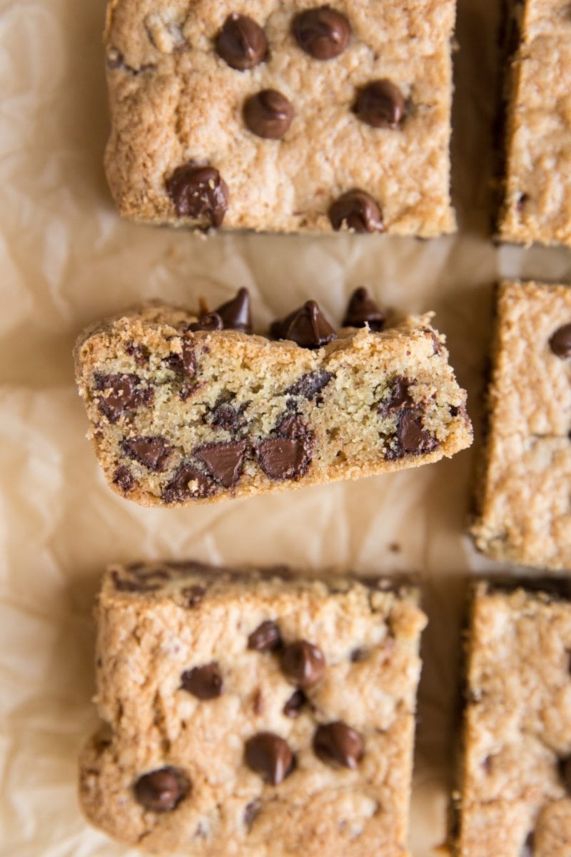 Gluten-Free Chocolate Chip cookie bars on parchment paper with a bar on its side to expose the inside