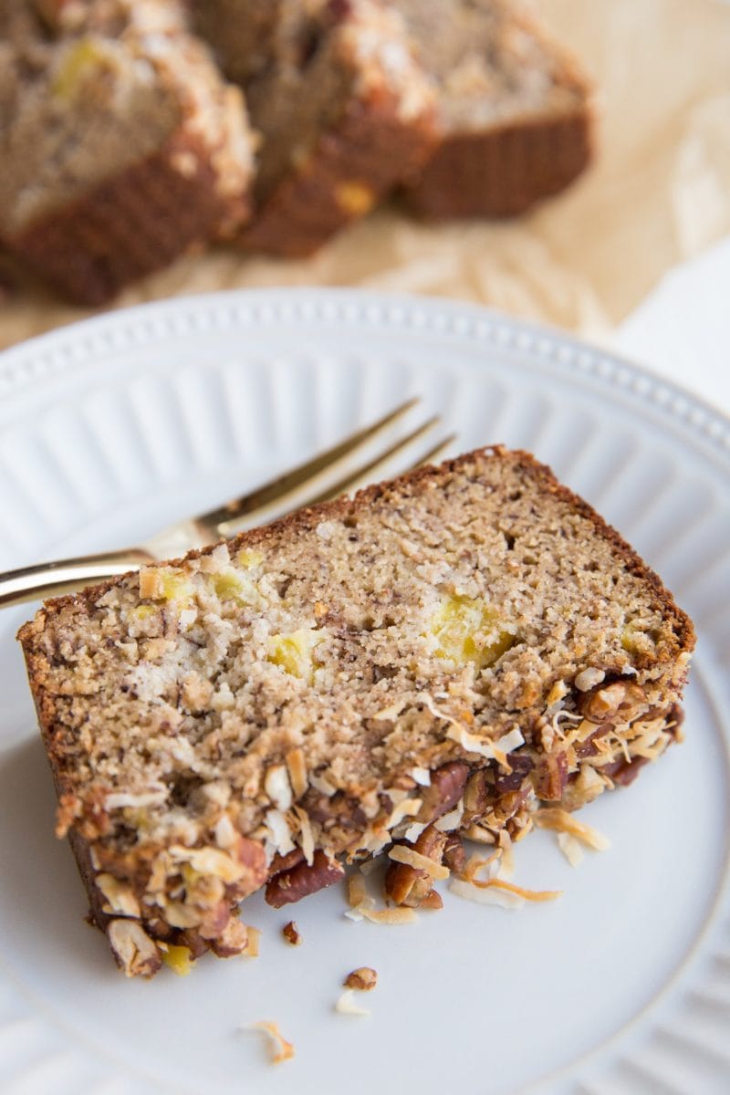 Slice of Grain-Free Hummingbird Bread on a plate with a loaf of bread in the background