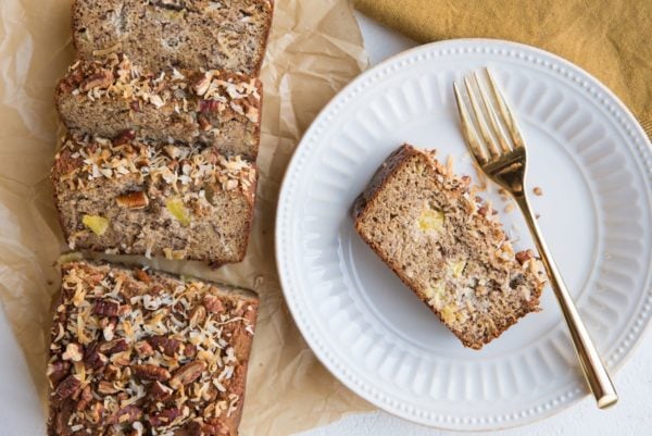 horizontal top down photo of loaf of hummingbird bread with a plate with a slice of bread