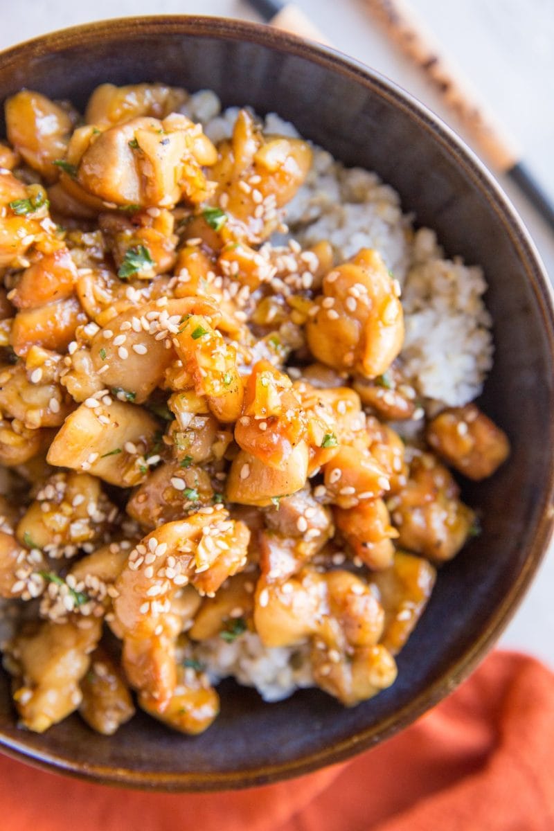 Close up top down image of honey garlic chicken on a bed of rice with a red napkin