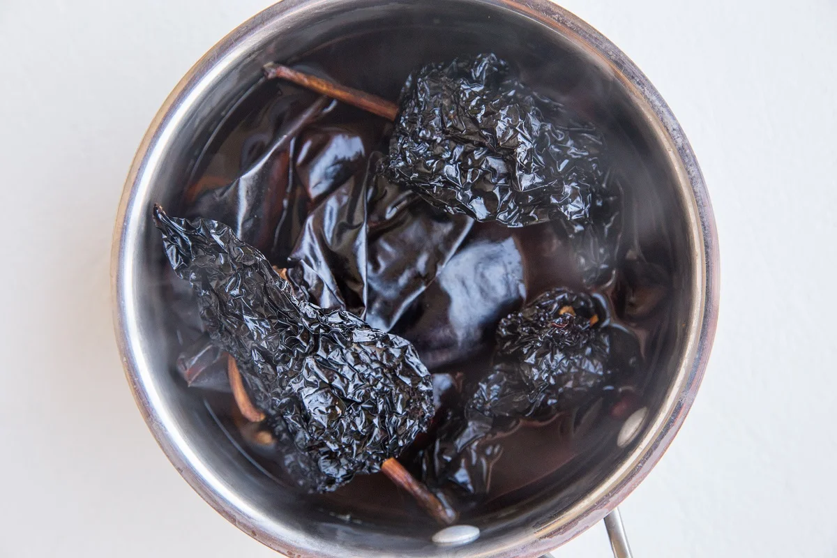 Dried chiles in boiling water in a saucepan to reconstitute the chiles