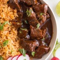 Close up top down image of chile colorado in a big bowl with Spanish rice and cilantro sprinkled on top