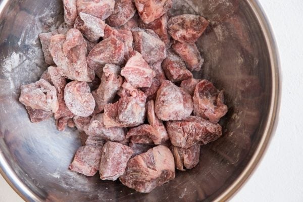 Beef tossed in flour in a mixing bowl