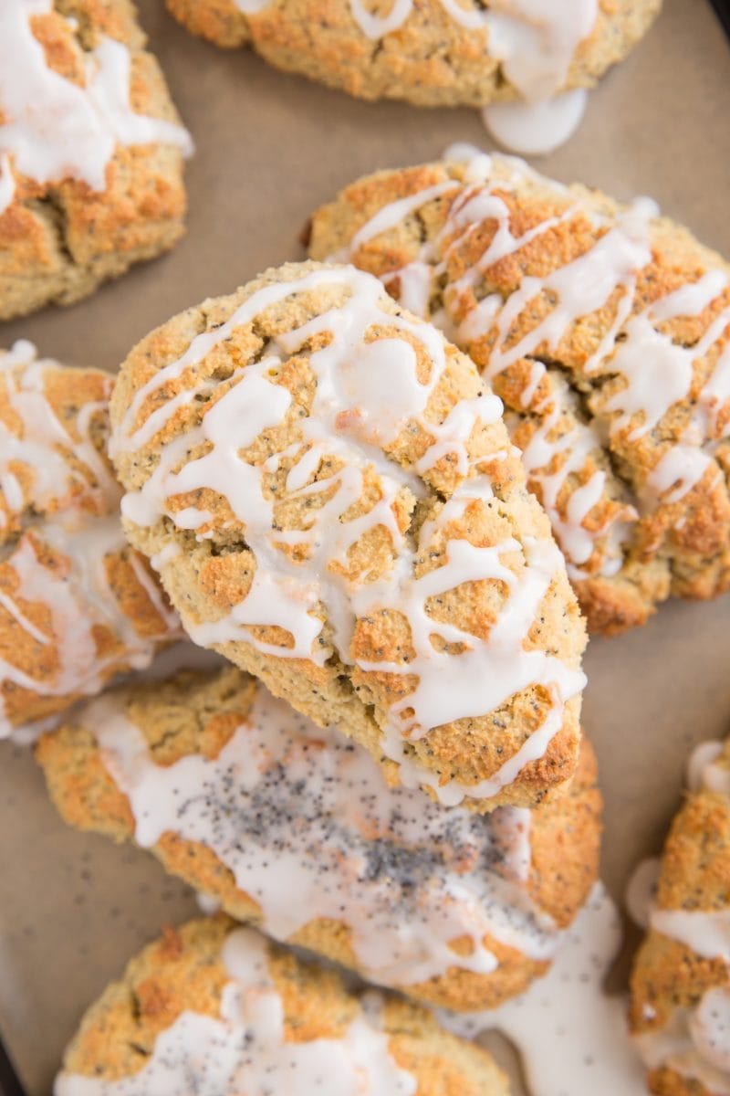 Baking sheet of keto lemon poppy seed scones stacked on top of each other with a glaze on top