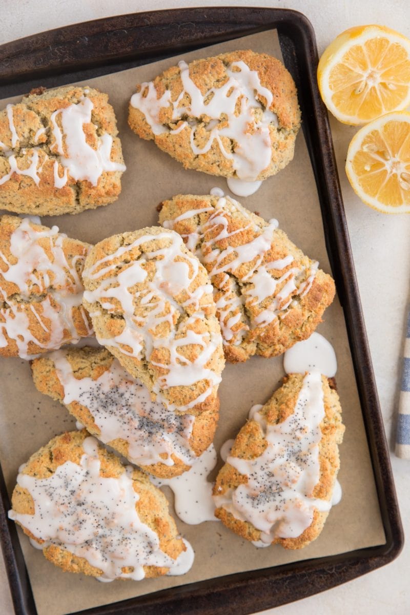 Stacks of keto scones on a baking sheet lined with parchment paper with a lemon off to the side and a striped napkin